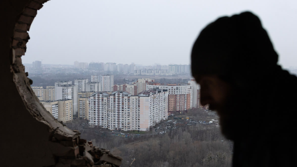 A photo of the view of a Russian city through the rubble of another building. A man’s silhouette can be seen through the view.