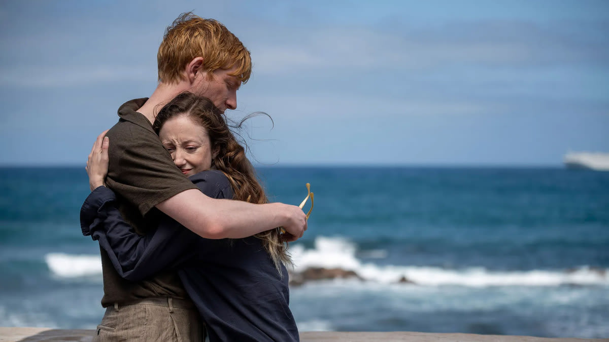 Andrea Riseborough and Domhnall Gleeson hug on the beach in a still from ‘Alice & Jack’