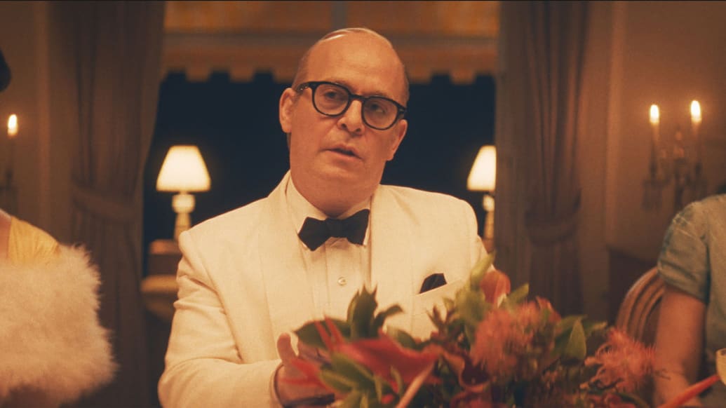 Tom Hollander sitting at a table in a still from ‘Feud: Capote: Capote vs The Swans’