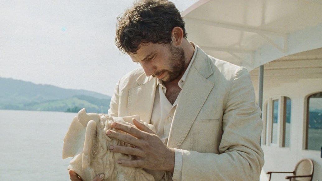 Josh O’Connor holds a statue bust in a still from ‘La Chimera’