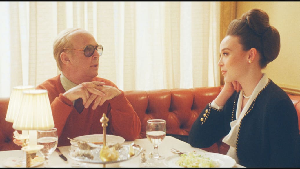 Ella Beatty and Tom Hollander talk at a dinner table in a still from ‘Feud: Capote vs The Swans’