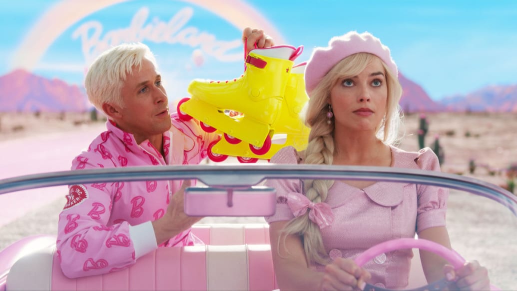 Margot Robbie as Barbie drives a pink car, as Ryan Gosling as Ken holds a pair of neon yellow roller skates in the backseat behind her.