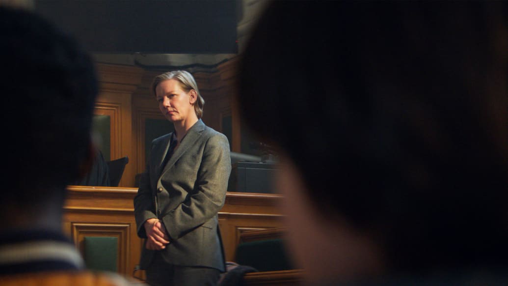 A woman stands at the front of a courtroom, before the jury.