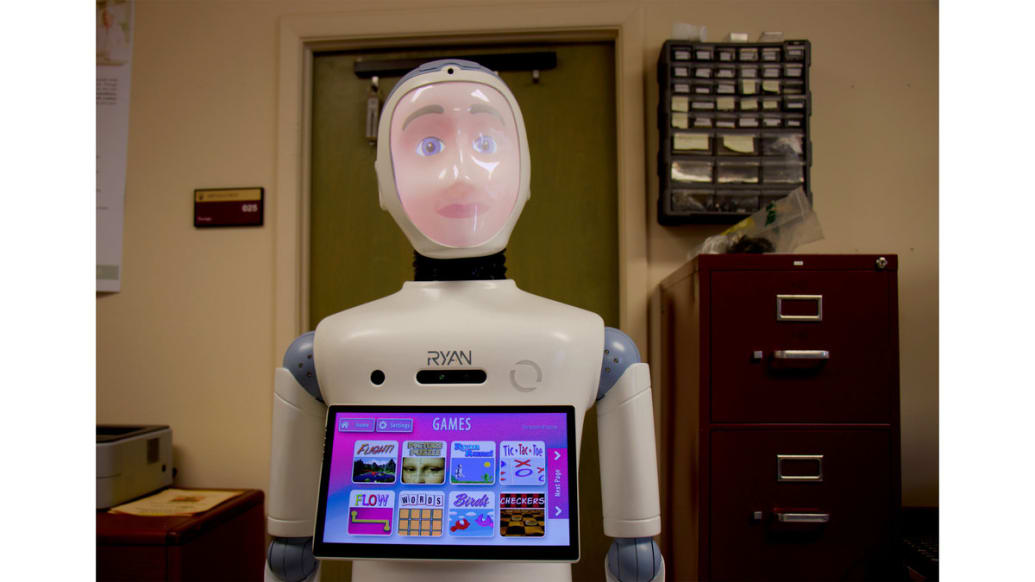 RYAN the robot stands with a touch screen on his chest in a room