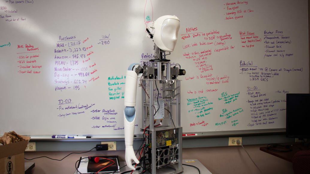 RYAN the robot stands in a classroom with his inner workings exposed