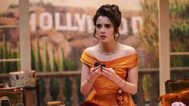 A still from ‘Choose Love’ that shows Laura Marano as Cami holding a wedding ring with the Hollywood sign behind her