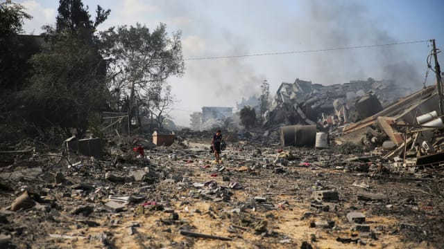 A photograph of a Palestinian boy walking by the buildings destroyed in the Israeli bombardment on al-Zahra, on the outskirts of Gaza City on October 20, 2023.