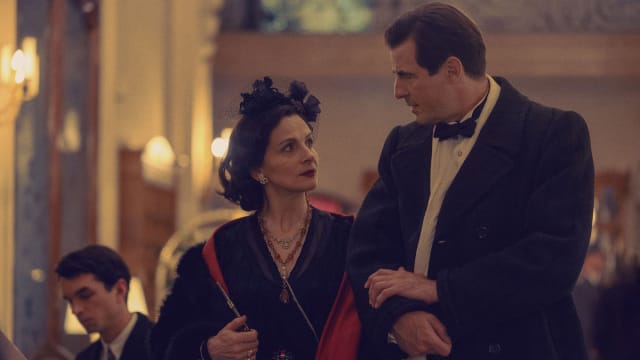 Juliette Binoche and Claes Bang arm in arm in a still from ‘The New Look,’ premiering February 14, 2024 on Apple TV+