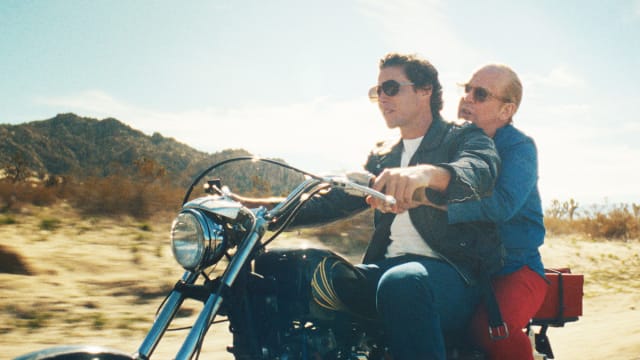Vito Scnabel and Tom Hollander ride a motorcycle in a still from ‘Feud: Capote vs The Swans’