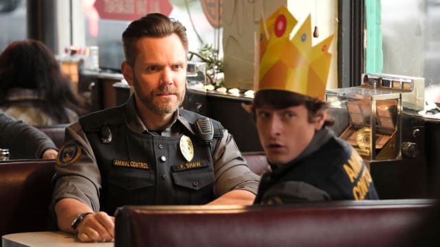 Joel McHale and Michael Rowland sit across from each other in a diner in a still from ‘Animal Control’