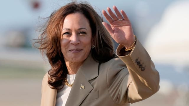 Kamala Harris waves to the crowd from the tarmac.