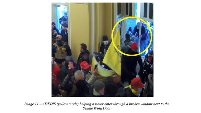 Prosecutors say this photo shows Miles Adkins helping a rioter enter through a broken window next to the Senate Wing door at the Capitol on Ja. 6, 2021.