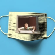 A photo illustration of John Early looking out of a window in a COVID mask