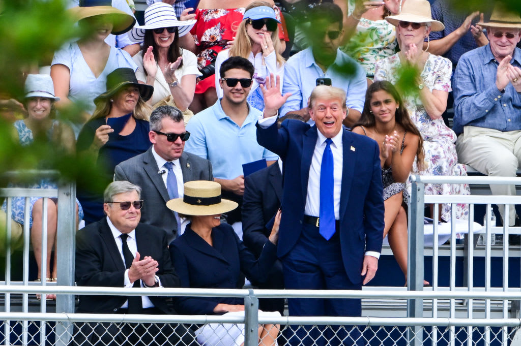 Donald Trump stands and waves in the direction of graduates at Oxbridge Academy.