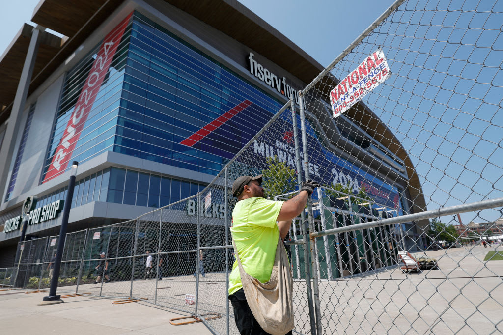 A security worker helps put up a fence outside Fiserv Forum, where the RNC begins Monday.