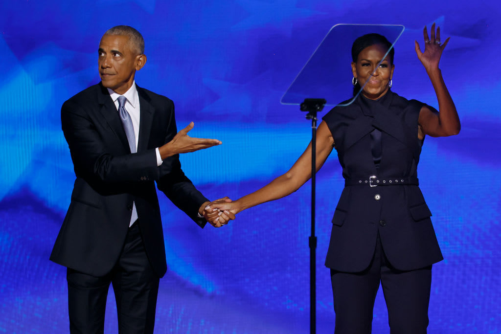 Former U.S. President Barack Obama, left greets Michelle Obama as he arrives to speak on stage during the second day of the Democratic National Convention in Chicago.