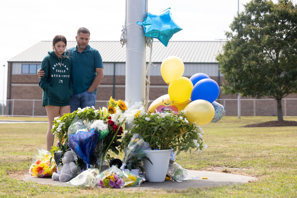 Sophomore student Ximena Verdin and her father stand at a makeshift memorial at Apalachee High School.