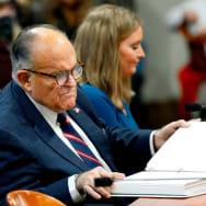 Rudy Giuliani looks at documents as he appears before the Michigan House Oversight Committee in Lansing, Michigan.