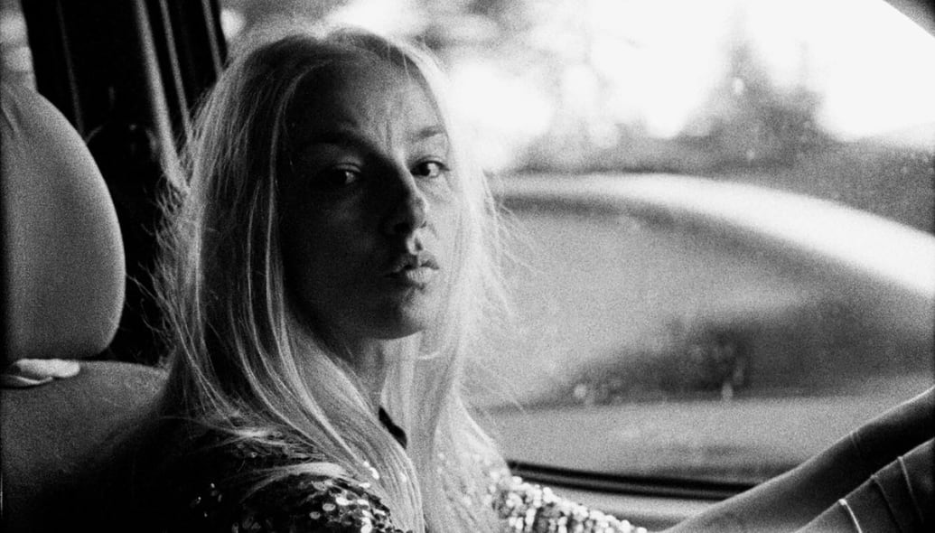 Ilinca Manolache sits in a car in a black and white still from Do Not Expect too Much From the End of the World