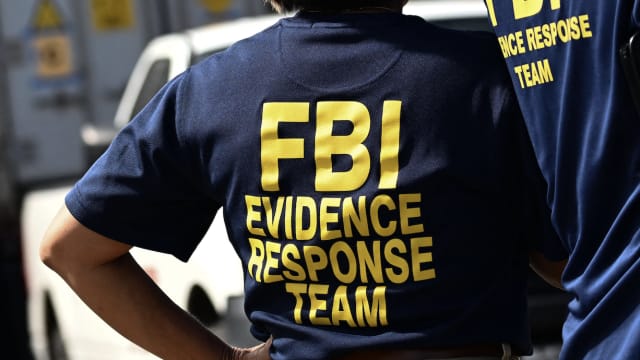 A photo of an FBI agent, back to camera, wearing am Evidence Response Team polo shirt.