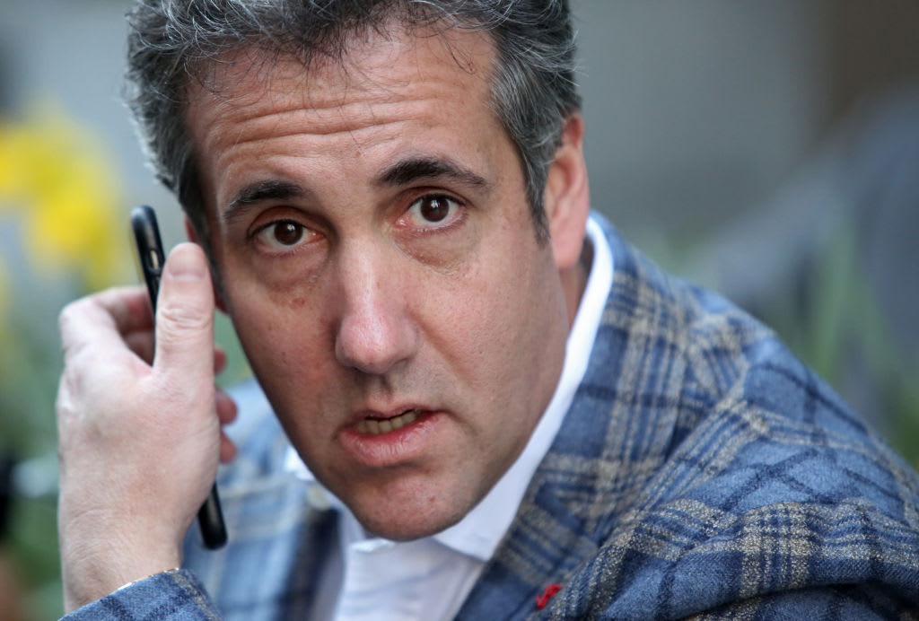 Michael Cohen answers his cellphone in public, wearing a plaid jacket.