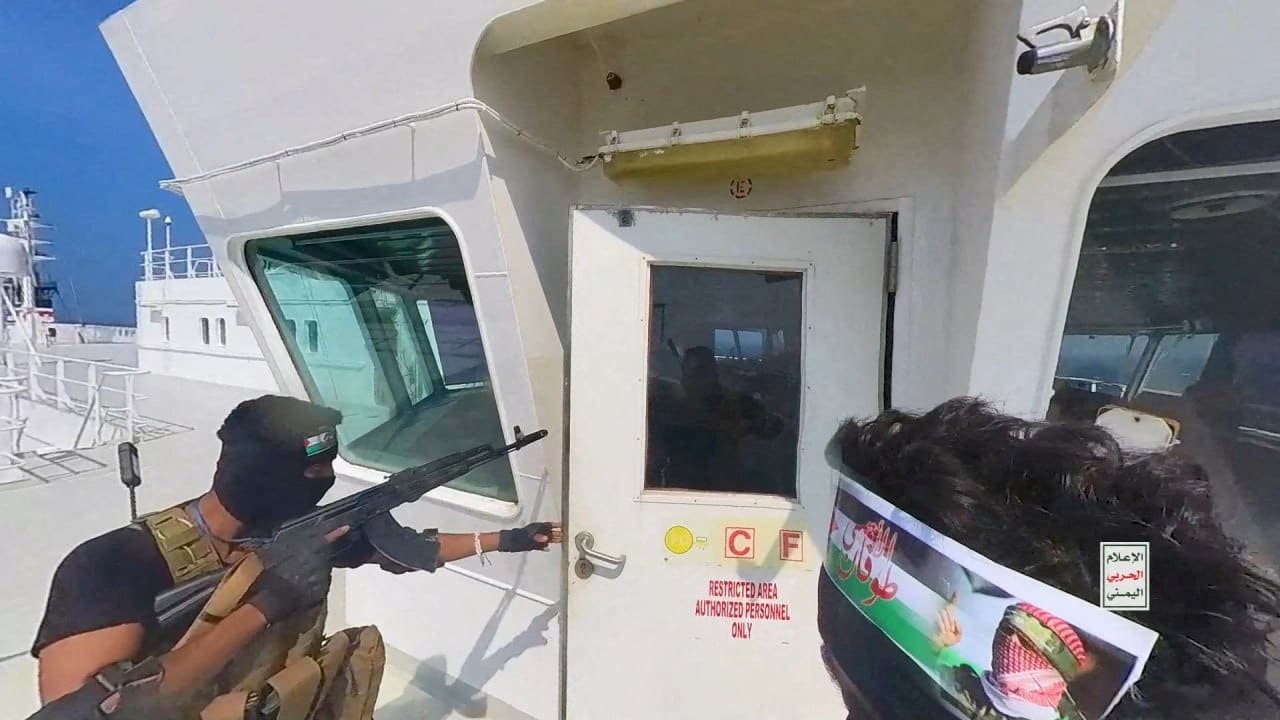 Houthi fighters open the door of the cockpit on a ship's deck in the Red Sea 