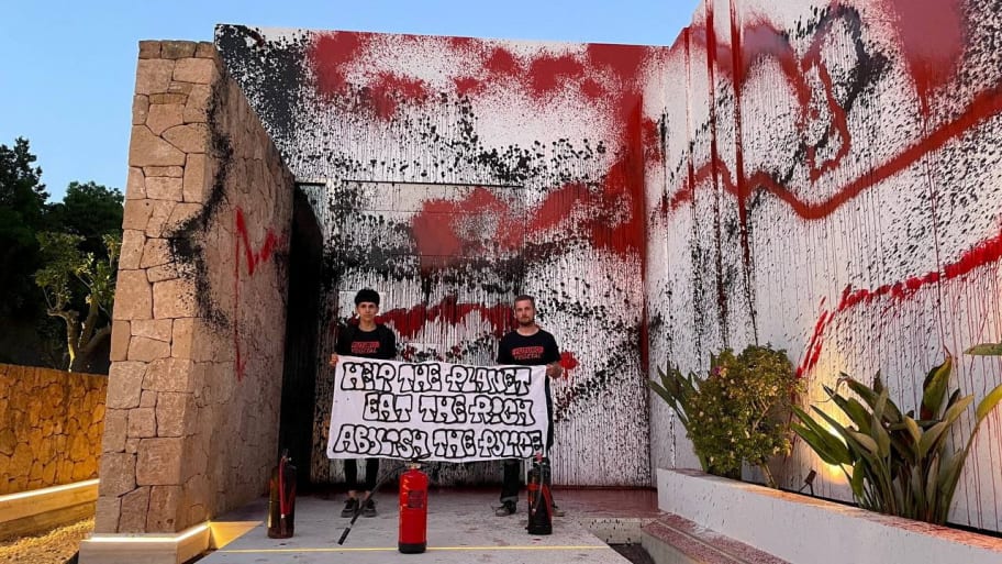 Two climate activists standing in front of Lionel Messi's house after vandalizing it. 