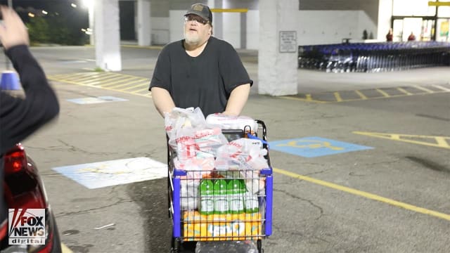 Matthew Brian Cooks walks out of a grocery store with a cart full of groceries.