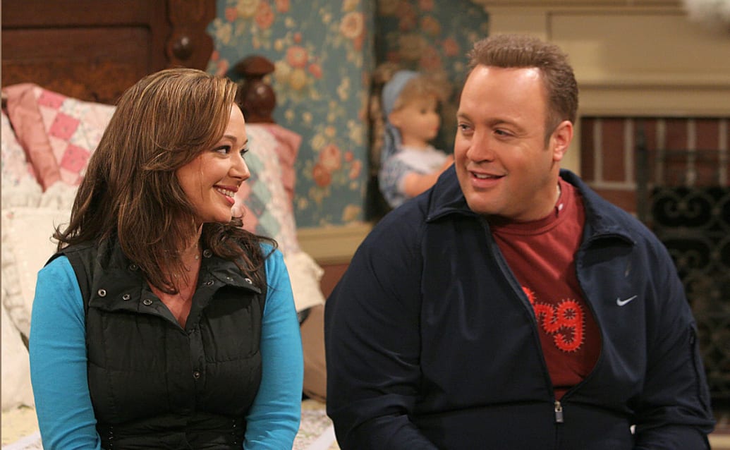 Kevin James and Leah Remini sit on a couch in a still from ‘The King of Queens’