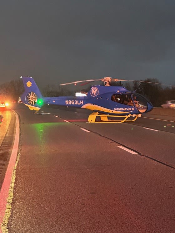 A helicopter on top of the interstate in Indiana, about to takeoff.
