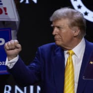 Republican presidential candidate and former U.S. President Donald Trump gestures as a supporter looks on during a Turning Point USA event.