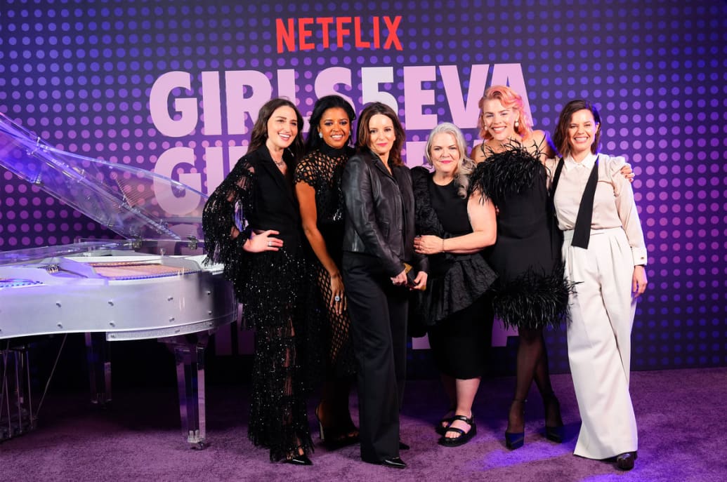 Sara Bareilles, Renee Elise Goldsberry, Tina Fey, Paula Pell, Busy Phillips and Meredith Scardino pose for a photo in front of a step and repeat for ‘Girls5Eva’