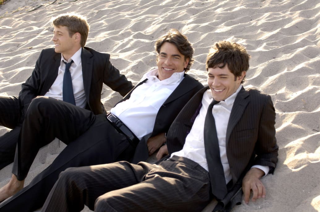 A picture of Benjamin McKenzie, Peter Gallagher, and Adam Brody in ‘The O.C.’ on the beach.
