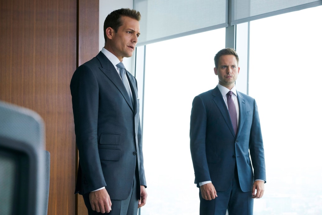 A still from ‘Suits’ that shows Gabriel Macht as Harvey Specter and Patrick J. Adams as Mike Ross standing nearby each other in an office
