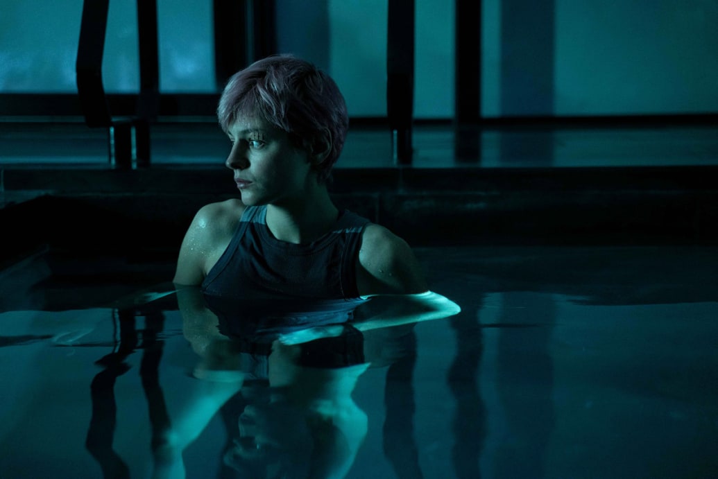 Emma Corrin sits in a pool in a still from ‘A Murder at the End of the World’