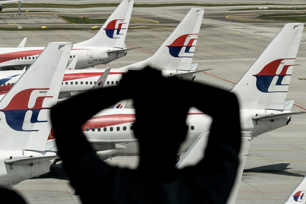 A photo of a man looking out at Malaysia Airlines' planes parked on a tarmac