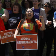 Women protest outside the Arizona legislature holding signs reading "Arizonans for Abortion Access"