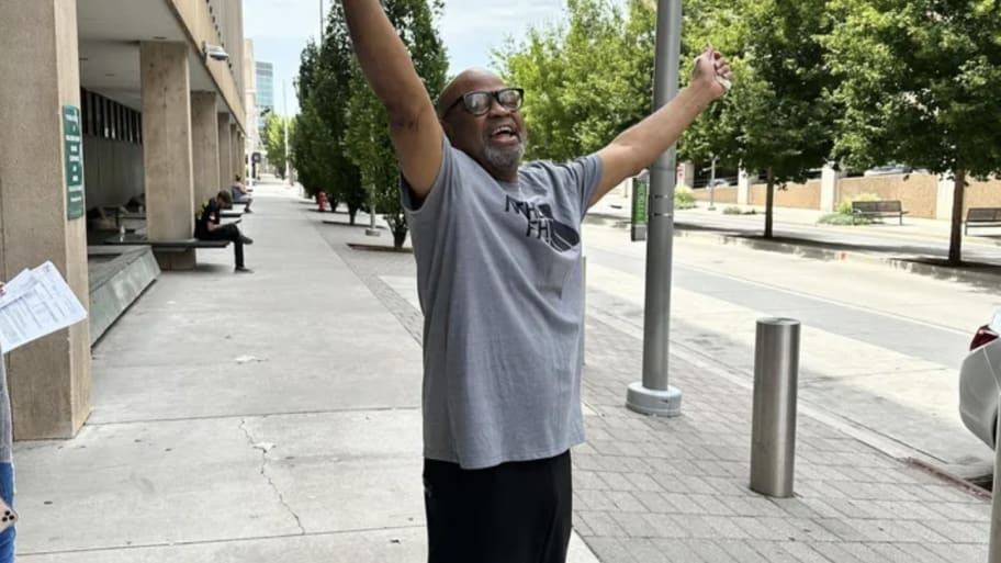 Glynn Simmons celebrates his freedom with his arms raised high.