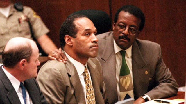 Lead defense attorney Johnnie Cochran puts his arm on O.J. Simpson’s shoulder during the football star’s murder trial.