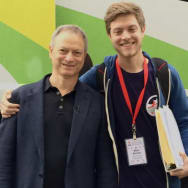 Gary Sinise, left, smiles with his son Mac, right, in front of a bus.