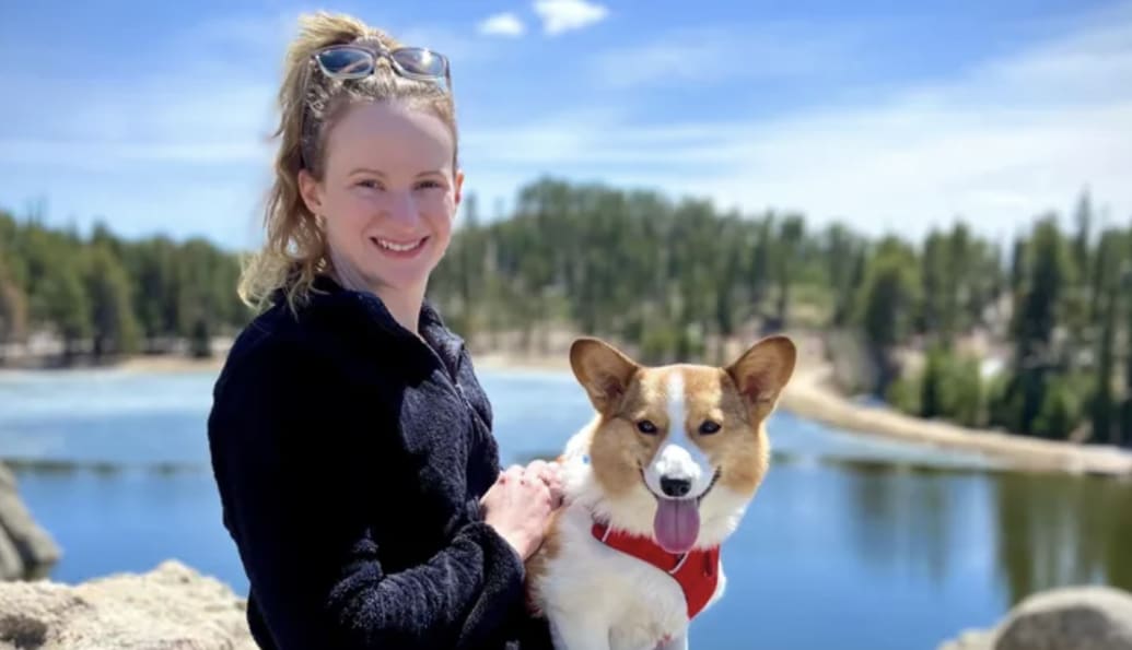 Betty Bowman smiles with a dog with a lake in the background.