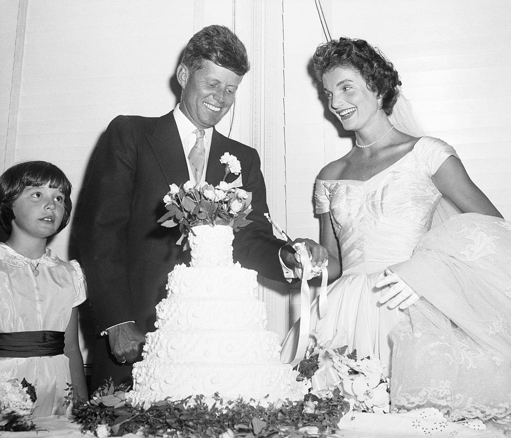 John F. Kennedy and Jackie Kennedy smile ahead of cutting their wedding cake.