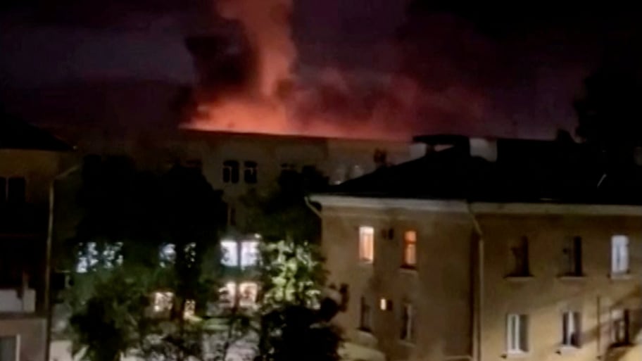 A plume of smoke is illuminated by a flash of light amid a drone attack in Pskov, Russia, in this still image obtained from social media video released August 30, 2023. 