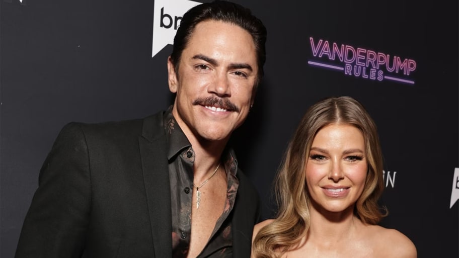Tom Sandoval and Ariana Madix smile on a red carpet.