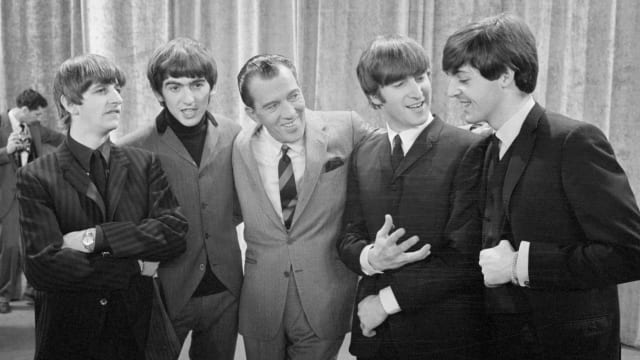 Ed Sullivan with his arms around the members of The BEatles