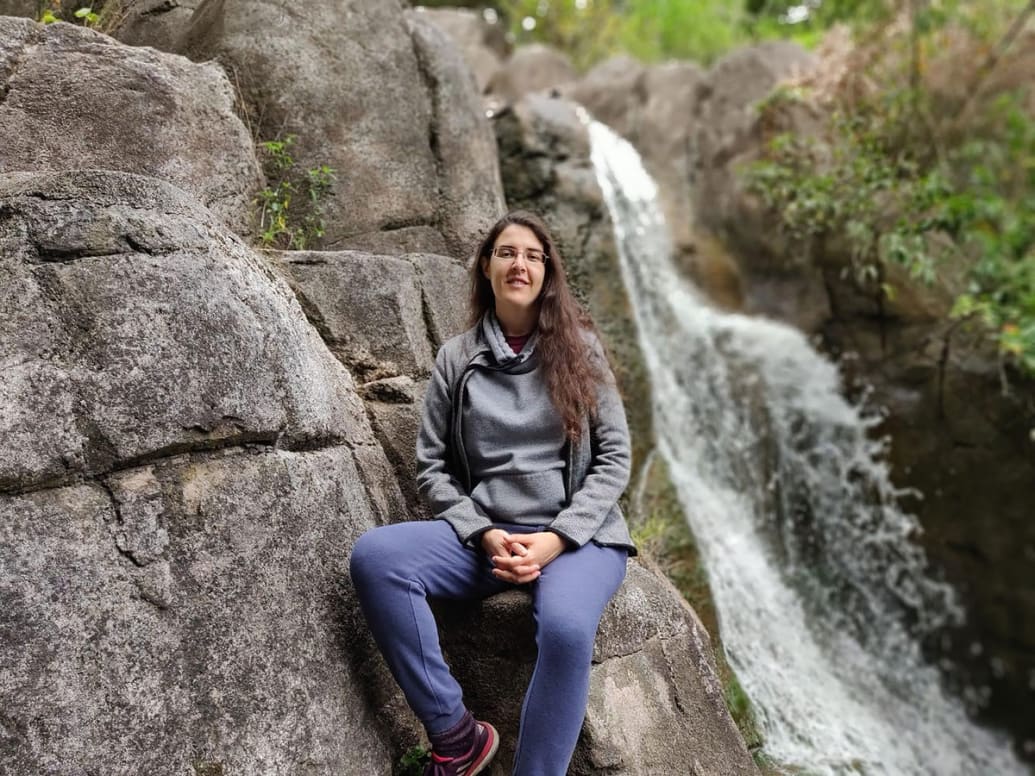 Elizabeth Tsurkov sitting next to a waterfall