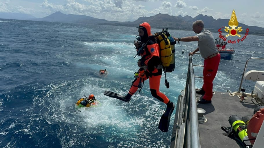 A scuba diver in red jumps into the ocean