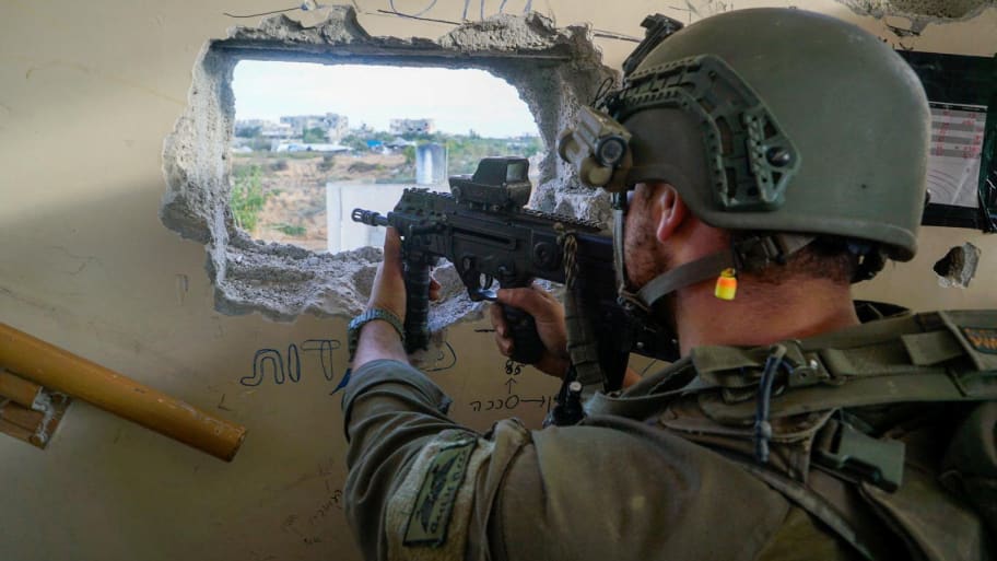 An Israeli soldier aims a weapon as they operate in the Gaza Strip, after a temporary truce between Israel and the Palestinian Islamist group Hamas expired, in this handout picture released on Dec. 1, 2023.