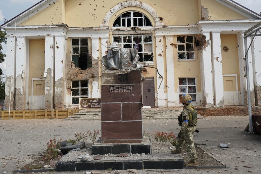 A Ukrainian soldier stands in front of the destroyed Lenin statue in Sudzha, Russia.